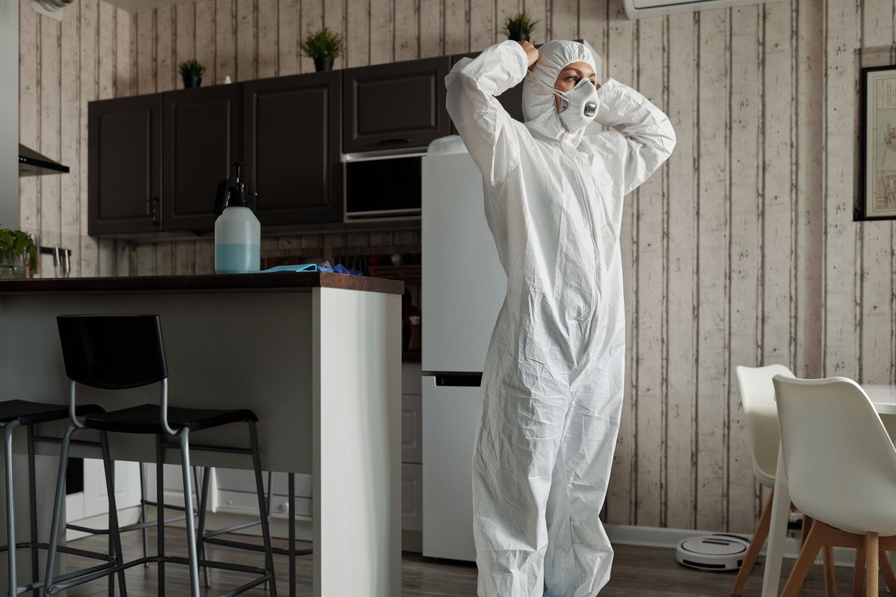 who-we-are Individual in protective gear standing in a contemporary kitchen setting during the day.